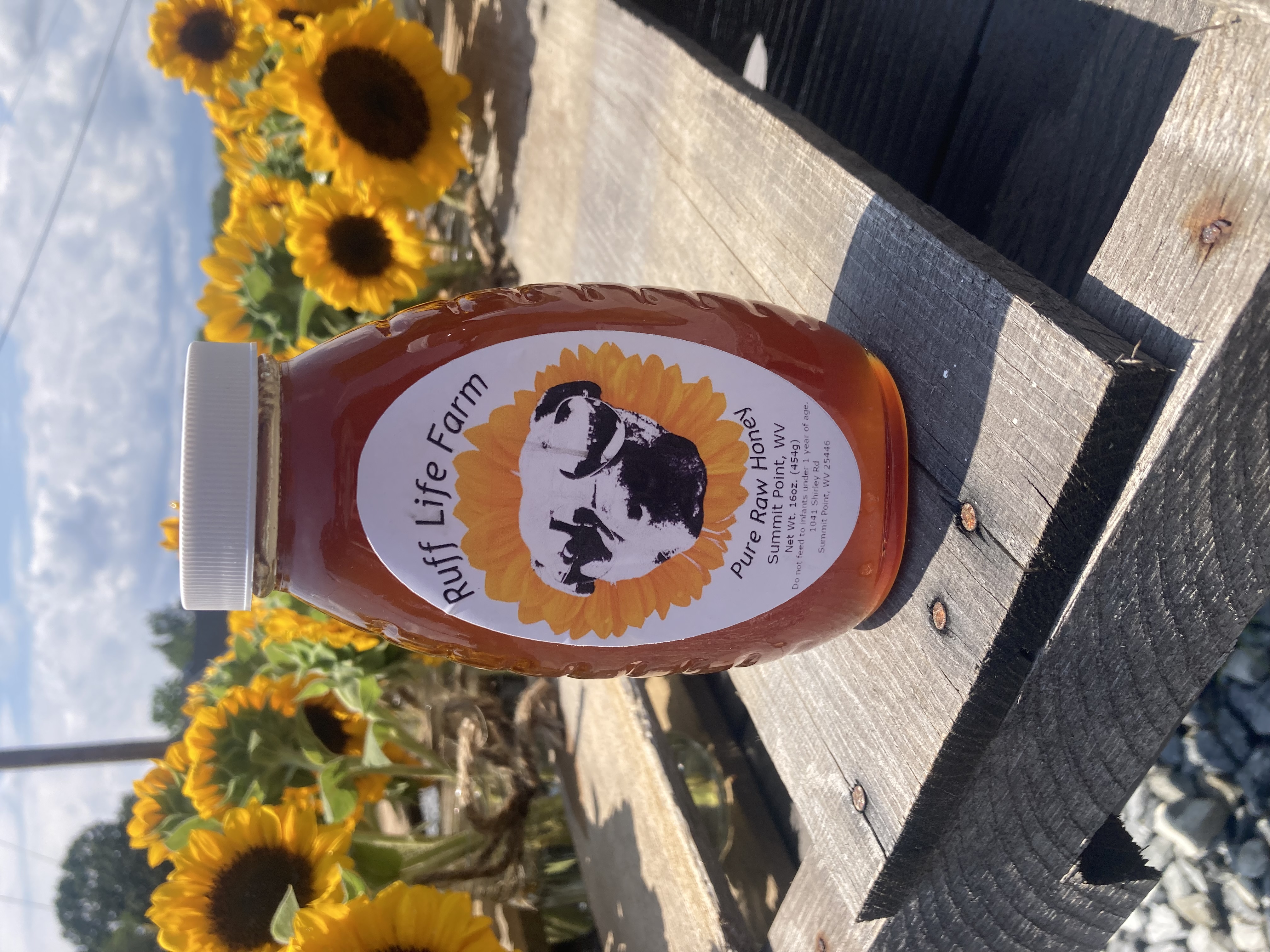 Our authentic Ruff Life Farm Raw Wildflower Honey jar surrounded by sunflowers